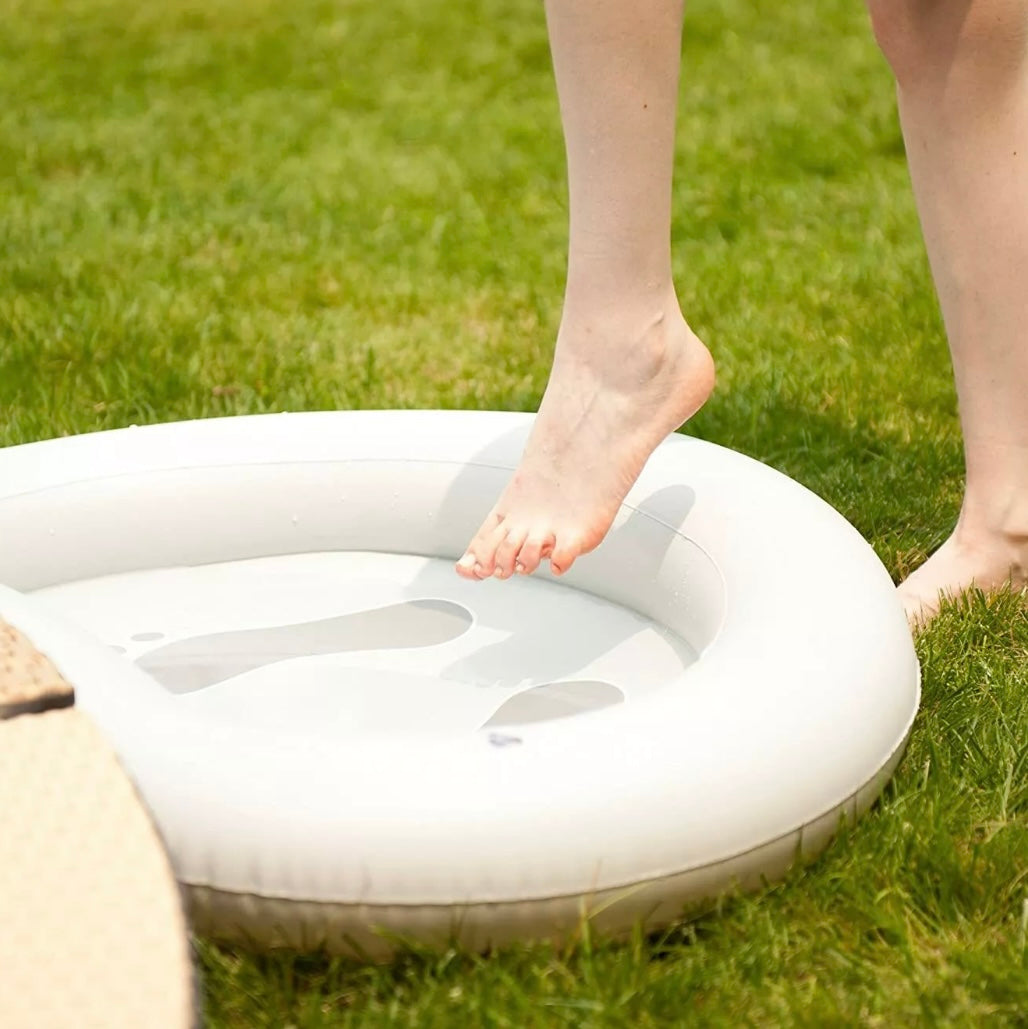White inflatable foot bath with water, a person's bare foot about to step in, set on green grass outdoors. - Home Interior Shop - MSpa Inflatable Pre-Wash Foot Bath