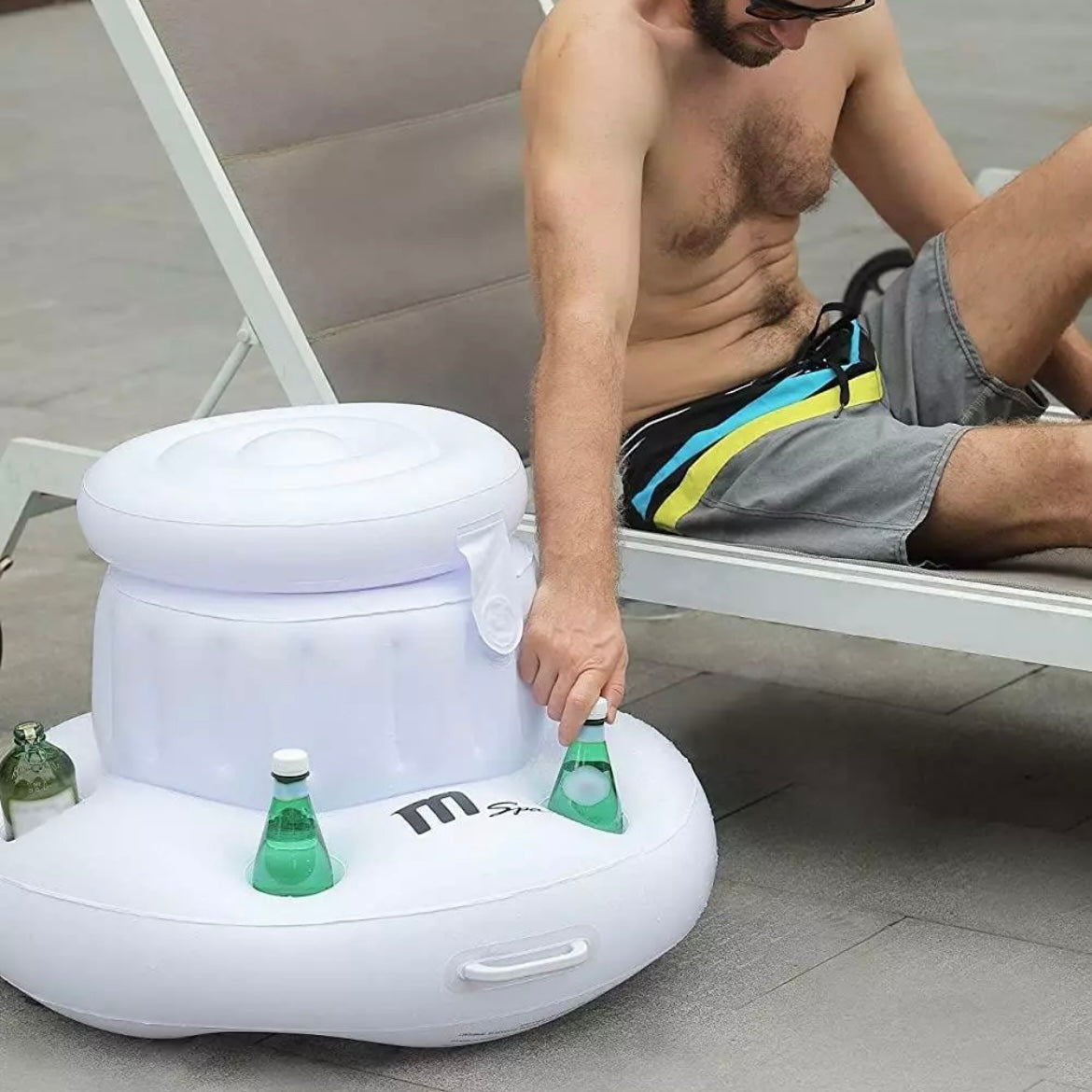 White inflatable ice box and snack box with integrated drink holders, holding green glass bottles, beside a man in swim. - Home Interior Shop - MSpa Inflatable Ice Box & Snack Box With Drinks Holders