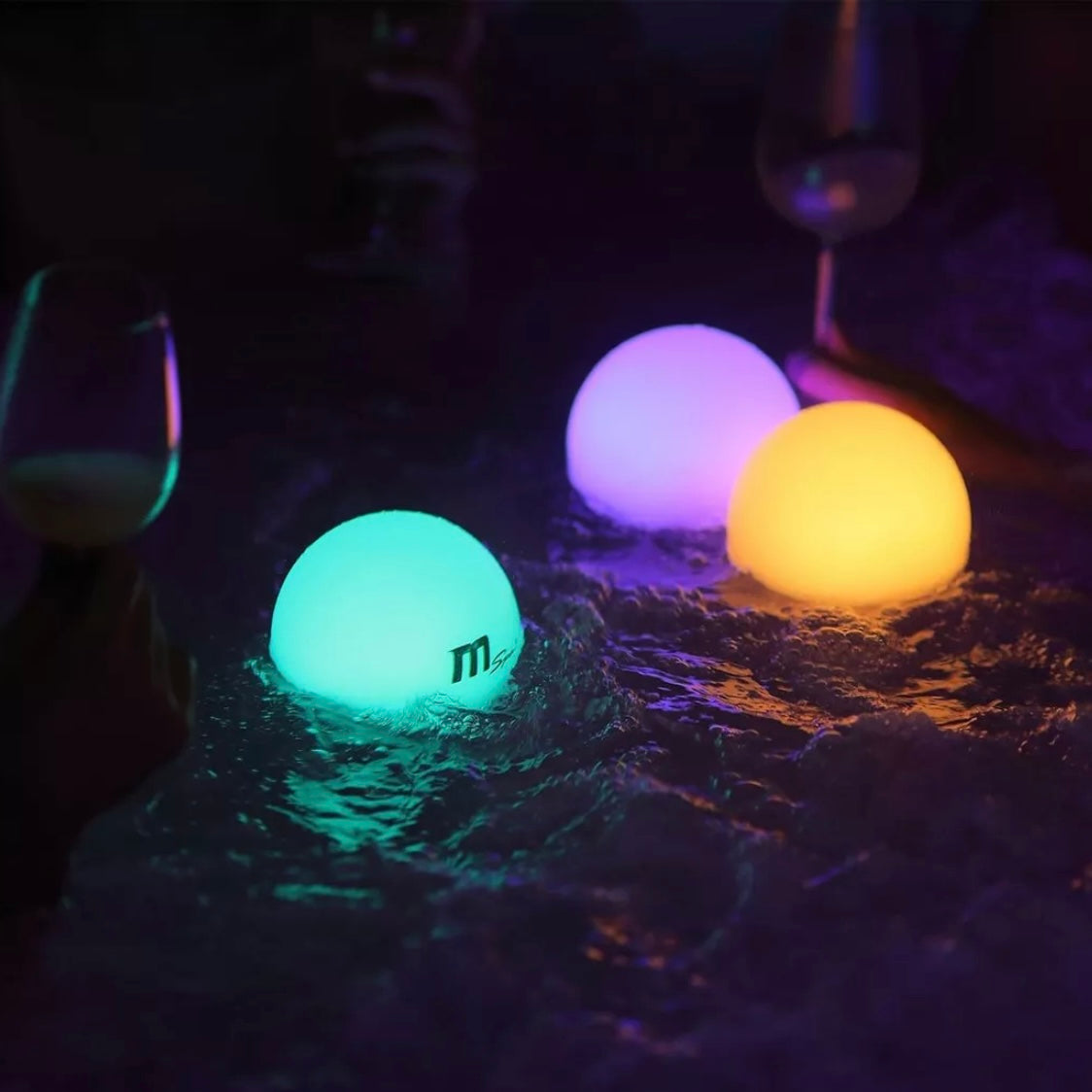 Three glowing MSpa floating LED ball lamps in aqua blue, purple, and warm yellow on pool water at night. - Home Interior Shop - MSpa Multicolour LED Floating Ball Lamp