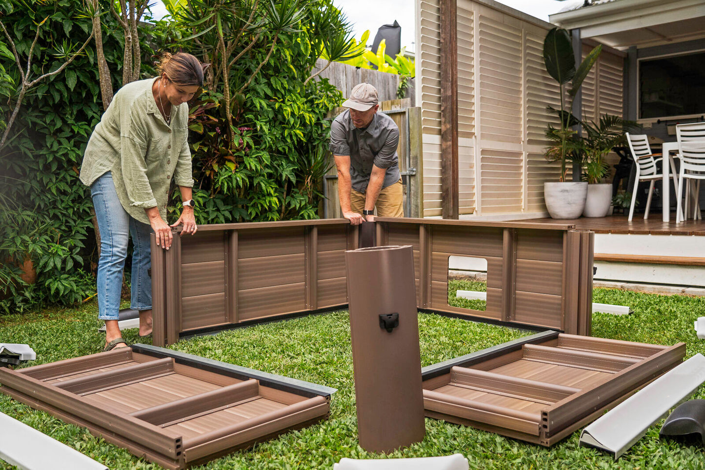 Two people assembling a brown portable hard frame hot tub outdoors on grass, surrounded by panels and a pump unit, with. - Home Interior Shop - MSpa Oslo 4-6 Person Portable Hard Frame Hot Tub - Amber