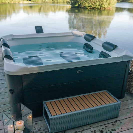Square grey MSpa Oslo portable hard frame hot tub with black headrests, filled with water, on wooden deck by a lake,. - Home Interior Shop - MSpa Oslo 4-6 Person Portable Hard Frame Hot Tub - Grey