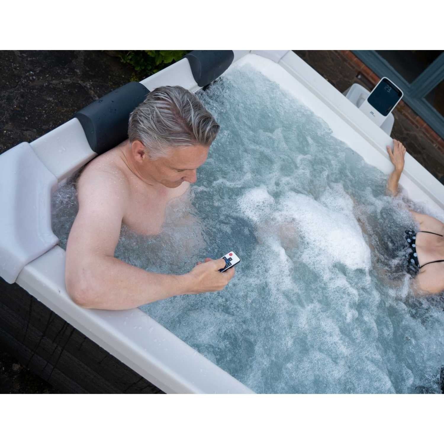 Grey square portable hard frame hot tub with two people relaxing in bubbling water, integrated headrests visible. - Home Interior Shop - MSpa Oslo 4-6 Person Portable Hard Frame Hot Tub - Grey