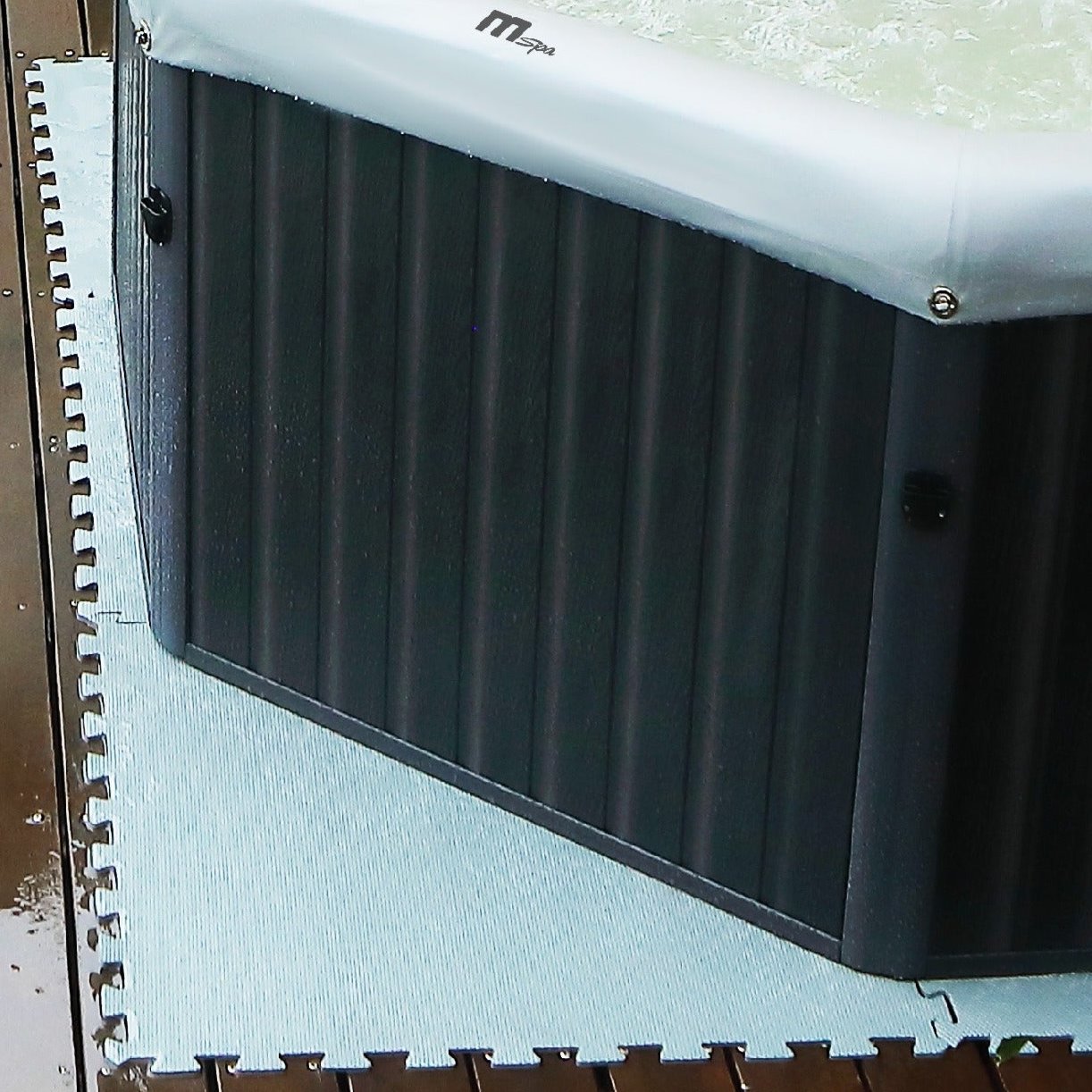 Black MSpa heat preservation foam mat with interlocking edges beneath a gray inflatable spa corner. - Home Interior Shop - MSpa Heat Preservation Foam Mats Eco Upgrade (Set of 9)