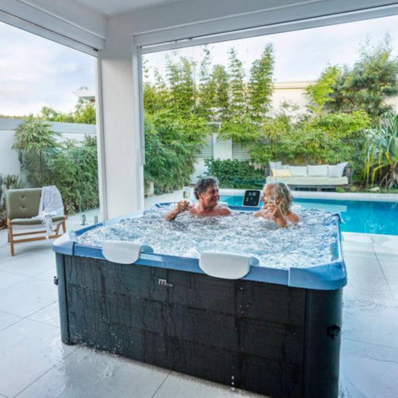 Square portable hard frame hot tub in sapphire blue with black exterior, two people relaxing inside on a covered patio near. - Home Interior Shop - MSpa Oslo 4-6 Person Portable Hard Frame Hot Tub - Sapphire